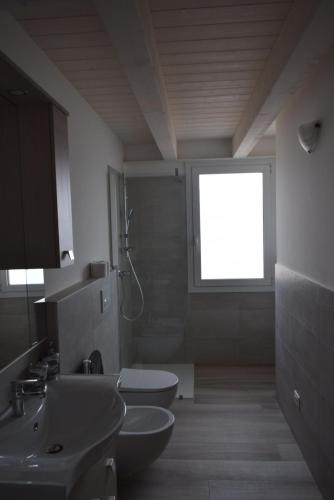 a bathroom with two sinks and a toilet and a window at Villa AMARE in Caorle