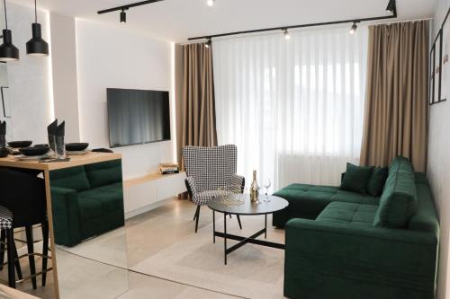 salon z zieloną kanapą i stołem w obiekcie President Lux Apartment w mieście Pale