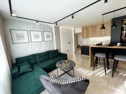 a living room with a green couch and a kitchen at President Lux Apartment in Pale