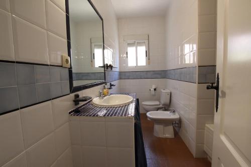 ein Badezimmer mit einem Waschbecken, einem WC und einem Spiegel in der Unterkunft CHALET CON PISCINA A 100m DE LA PLAYA LA MANGA in La Manga del Mar Menor