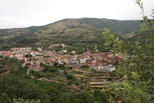 a town on a hill with mountains in the background at Hostal Yuste in Garganta la Olla