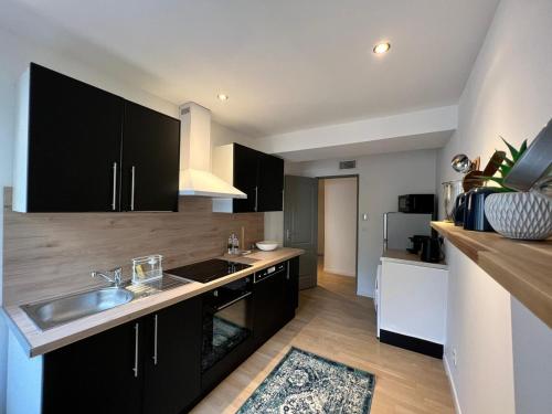 una cocina con armarios negros y fregadero en Le Rêve Bleu Appartement Hyper-centre en Carcassonne
