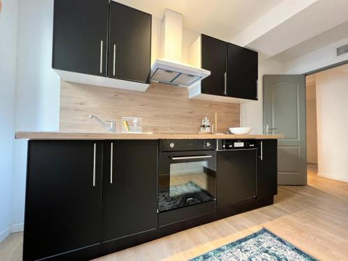 - une cuisine avec des armoires noires et une cuisinière dans l'établissement Le Rêve Bleu Appartement Hyper-centre, à Carcassonne