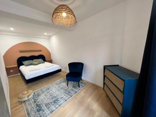 1 dormitorio con 1 cama, 1 silla y 1 lámpara de araña en Le Rêve Bleu Appartement Hyper-centre en Carcasona
