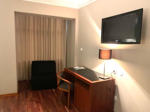 a hotel room with a desk and a television on the wall at Hotel Puma in Maia