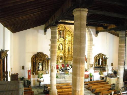 a church with a large altar and wooden pews at Hostal Yuste in Garganta la Olla