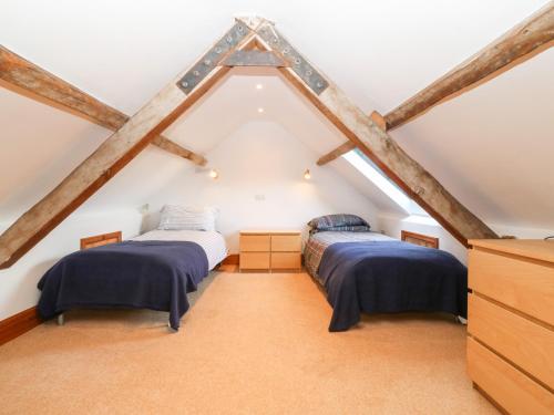 two beds in a attic room with wooden beams at Gladstone in Pwllheli