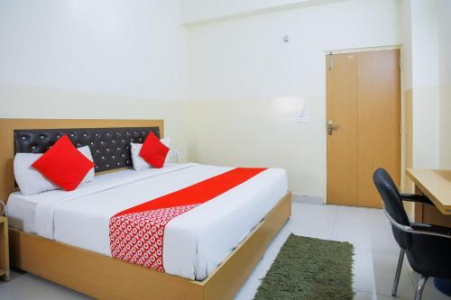 a bedroom with a bed with red pillows and a desk at Capital O Crosswind Gold in Indirapuram
