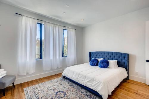 een slaapkamer met een bed met een blauw hoofdeinde en ramen bij 4 Story Home Mins To Downtown Houston with City Views in Houston