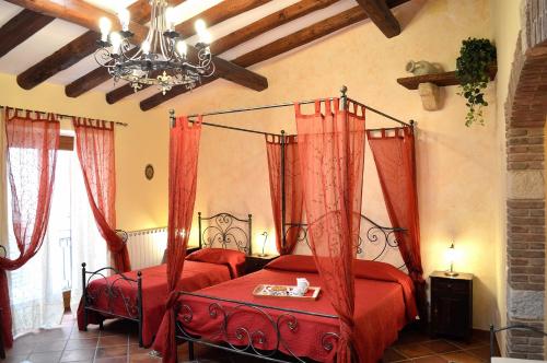 ペトラリーア・ソッターナにあるIl Castelloのベッドルーム1室(赤いカーテンとシャンデリア付きのベッド2台付)
