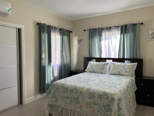 a bedroom with a bed and two windows at Seamist villa @Oceanpointe Lucea comfy 2BR w/pool gym & parking in Lucea