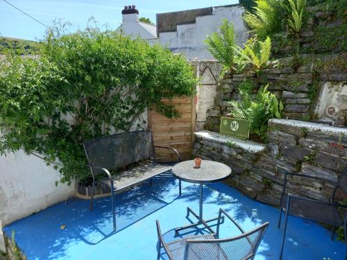 a patio with a table and chairs on a blue floor at Truly Paradise Cottage in Golant