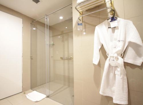 y baño con ducha y albornoz blanco. en Aparta Hotel Torres de Suites, en Quito