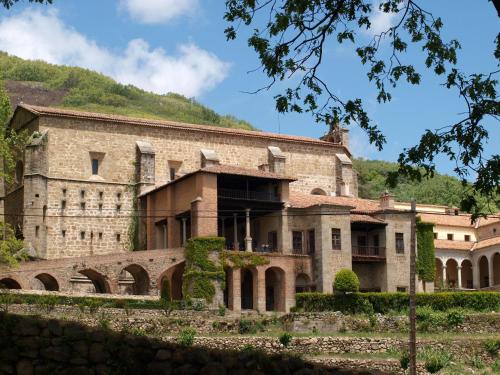 an old stone building with a mountain in the background at Hostal Yuste in Garganta la Olla
