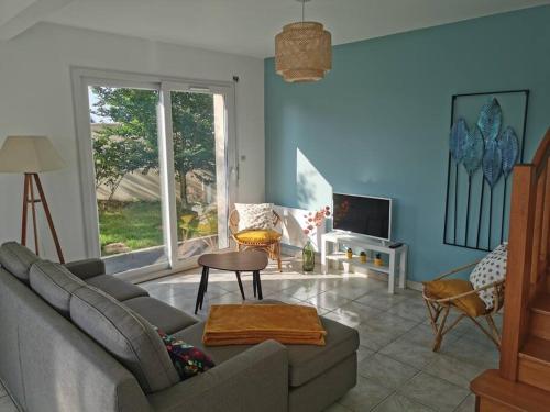 uma sala de estar com um sofá e uma televisão em Maison de vacances proche des plages et du GR34 em Sibiril