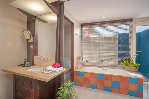 a bathroom with two sinks and a tub and a window at Villa Maorie 1 chambre avec piscine privée in Le François