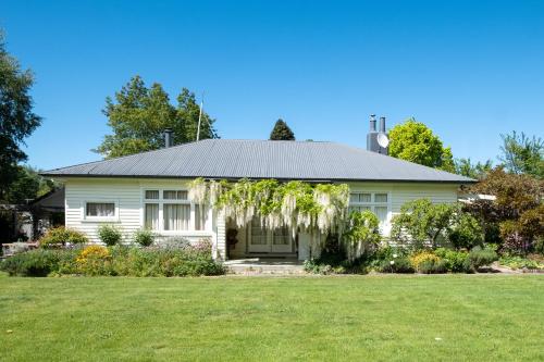 a white house with a green yard at Harrogate Gardens Motel in Hanmer Springs