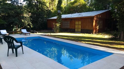 a pool with a chair next to a cabin at Entrepinos Mendoza in Ciudad Lujan de Cuyo