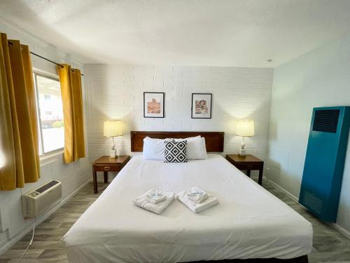1 dormitorio con 1 cama grande y 2 toallas. en The Postcard Motel, en Seligman