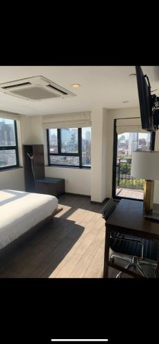 a bedroom with a bed and a desk and windows at Orchard Street Hotel in New York