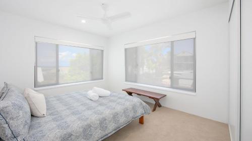 Cette chambre blanche dispose d'un lit et de deux fenêtres. dans l'établissement Talinga 4, à Yamba