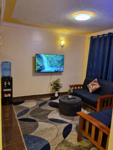 a living room with a couch and a tv on the wall at Spacious 1 Bedroom Mirema Drive with Parking in Nairobi