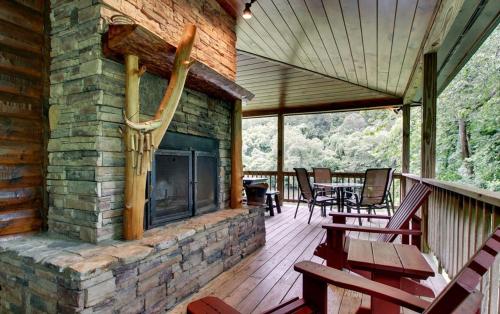 a screened porch with a fireplace on a log house at Astounding River View in Copperhill