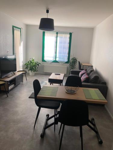 uma sala de estar com uma mesa e cadeiras e um sofá em Superbe Appartement en plein centre ville. em La Roche-sur-Yon