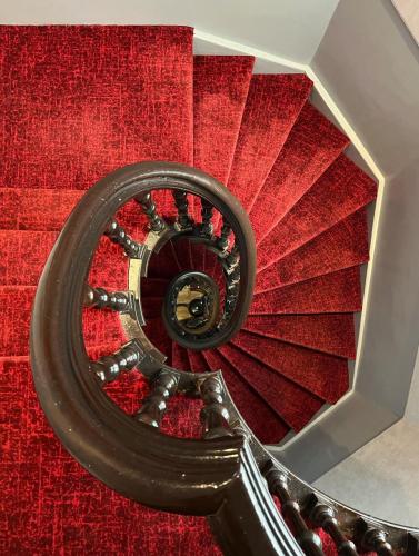 a red spiral stair case with a red carpet at Facade Hotel Amsterdam in Amsterdam
