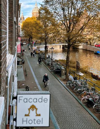 a man riding a bike down a street with a hotel sign at Facade Hotel Amsterdam in Amsterdam