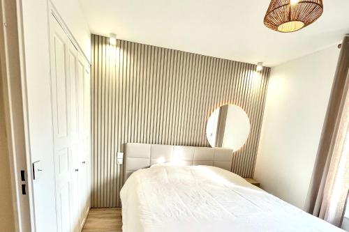 une chambre avec un lit blanc et un miroir dans l'établissement Magnifique 2 Chambres Terrasse et Parking, à Saint-Tropez