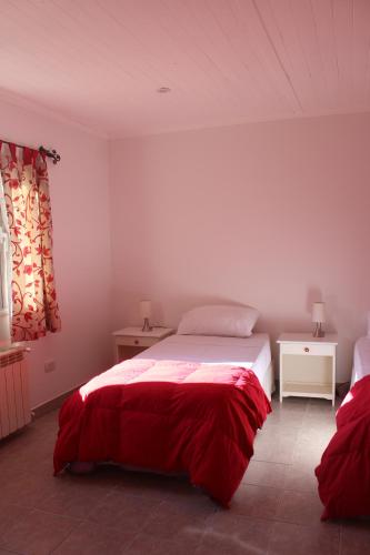a bedroom with a bed with a red blanket at HOSPEDAR CALAFATE - Los Lupinos in El Calafate