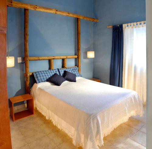1 dormitorio con 1 cama grande y paredes azules en Cabañas Costa Vergel en Los Reartes