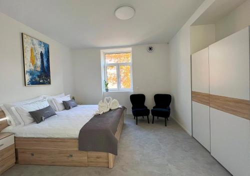 a bedroom with a bed with two chairs and a window at Villa Riverside in Ljubljana