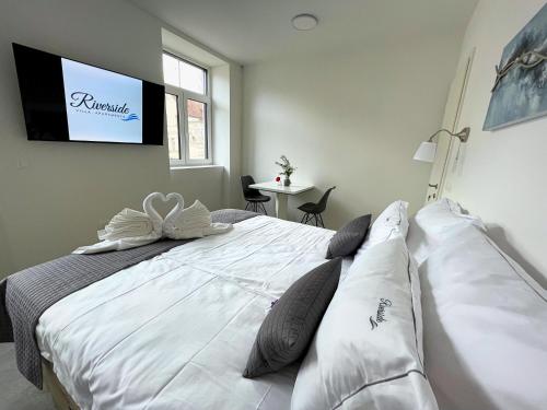 a bedroom with a large white bed with a tv on the wall at Villa Riverside in Ljubljana