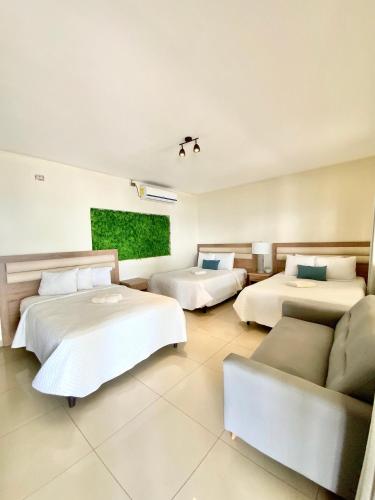 a hotel room with three beds and a couch at Paradise Surf Hotel in San Miguel