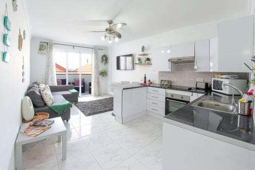 a white kitchen with a couch and a table at Gorgeous Los Diamantes Home by LoveTenerife in Los Cristianos