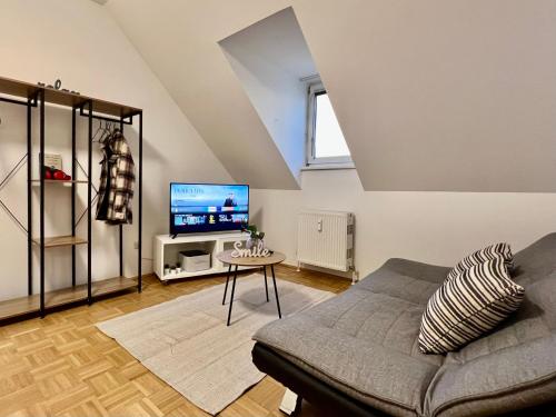 een woonkamer met een bank en een tv bij urbanstays Linz Landstraße - city center - near casino in Linz