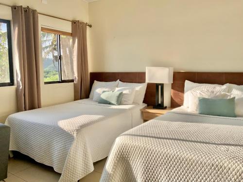 1 dormitorio con 2 camas y ventana en Paradise Surf Hotel, en San Miguel