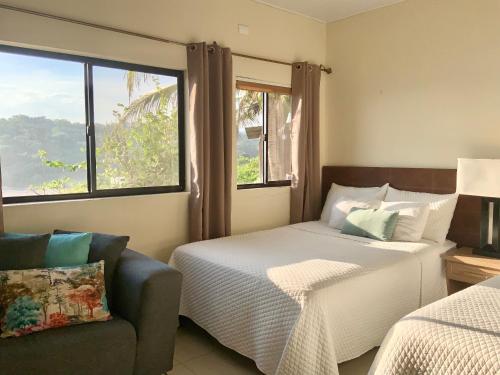 a bedroom with two beds and a couch and a window at Paradise Surf Hotel in San Miguel