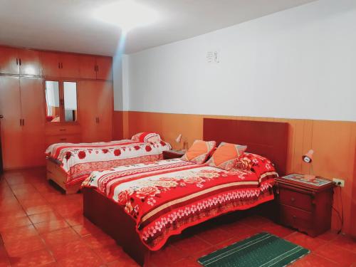 two beds in a room with red walls at Hotel Central in Latacunga