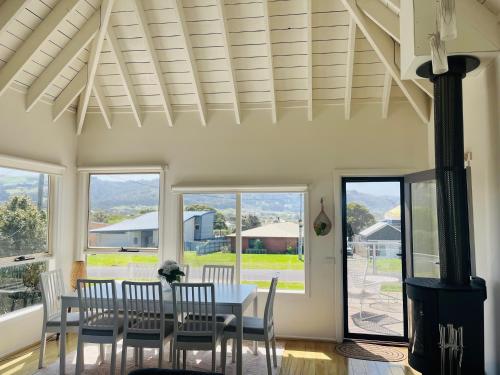 a dining room with a table and chairs and windows at Apollo Bay Rocket House l Pet-Friendly Free Wi-Fi in Apollo Bay