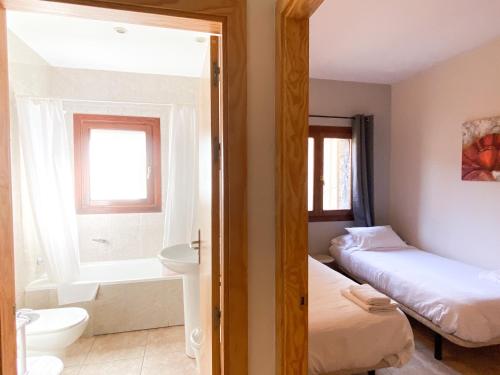 um quarto com 2 camas e uma casa de banho com banheira em Disfruta De La Naturaleza - Vistas al Rio - Luz Natural - 6pax em Canillo