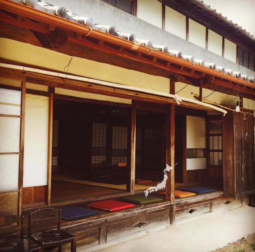 a building with a porch with a dog sitting on the floor at 古民家一棟貸しナノビレッジ岡山 in Kaga