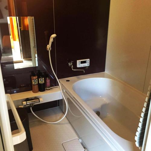 a bathroom with a bath tub with a hose attached at 古民家一棟貸しナノビレッジ岡山 in Kaga
