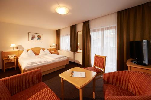 a hotel room with a bed and chairs and a tv at Hotel Wagrainerhof in Wagrain