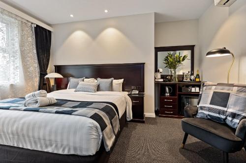 a bedroom with a large bed and a chair at International Hotel Wagga Wagga in Wagga Wagga