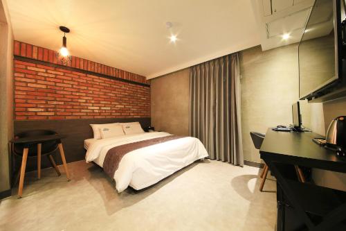 a bedroom with a bed and a brick wall at DUNE45 in Suwon