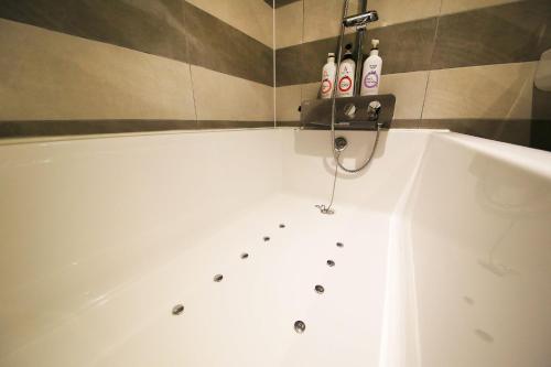 a bath tub with three bottles on the side of it at DUNE45 in Suwon