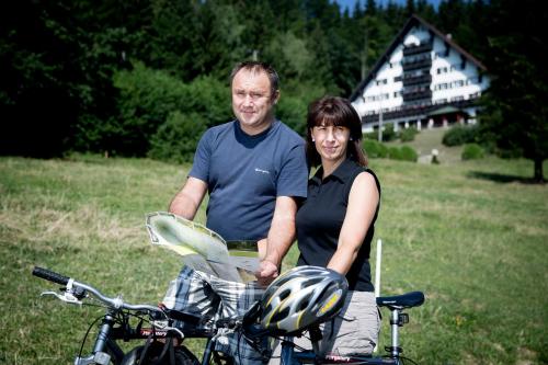 a man and a woman standing next to a bike at Hotel Tisa Pohorje in Pohorje